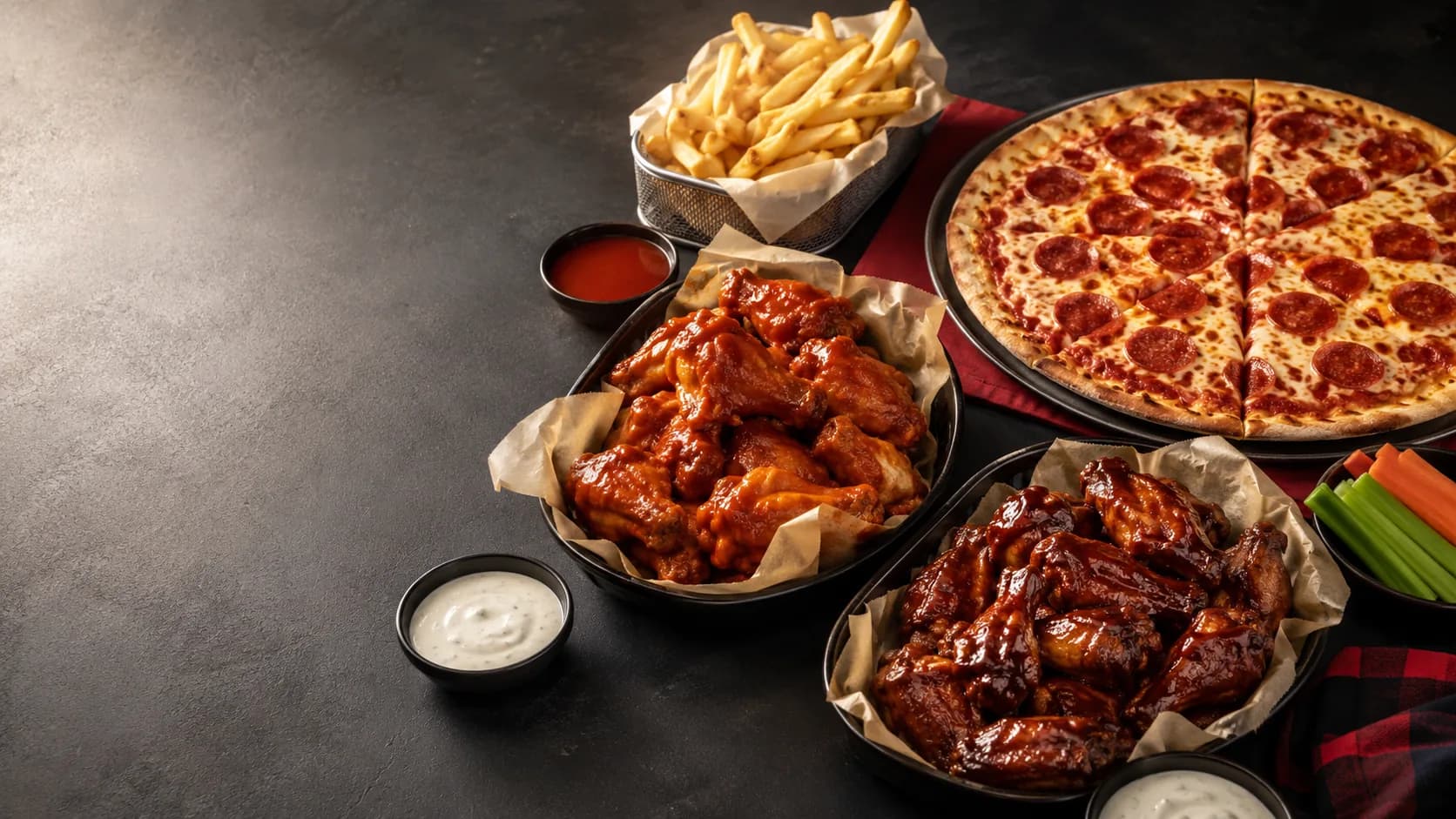 Best Wings N Pies hero feast with wings, pizza, fries, and sauces